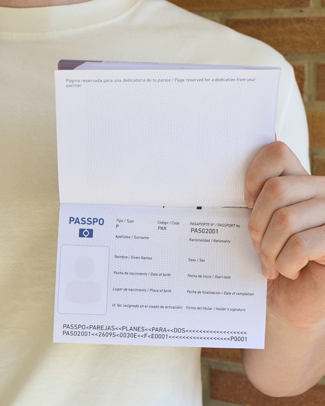 Persona mostrando el PASSPO Planes para dos abierto por sus páginas de identificación y dedicatoria.